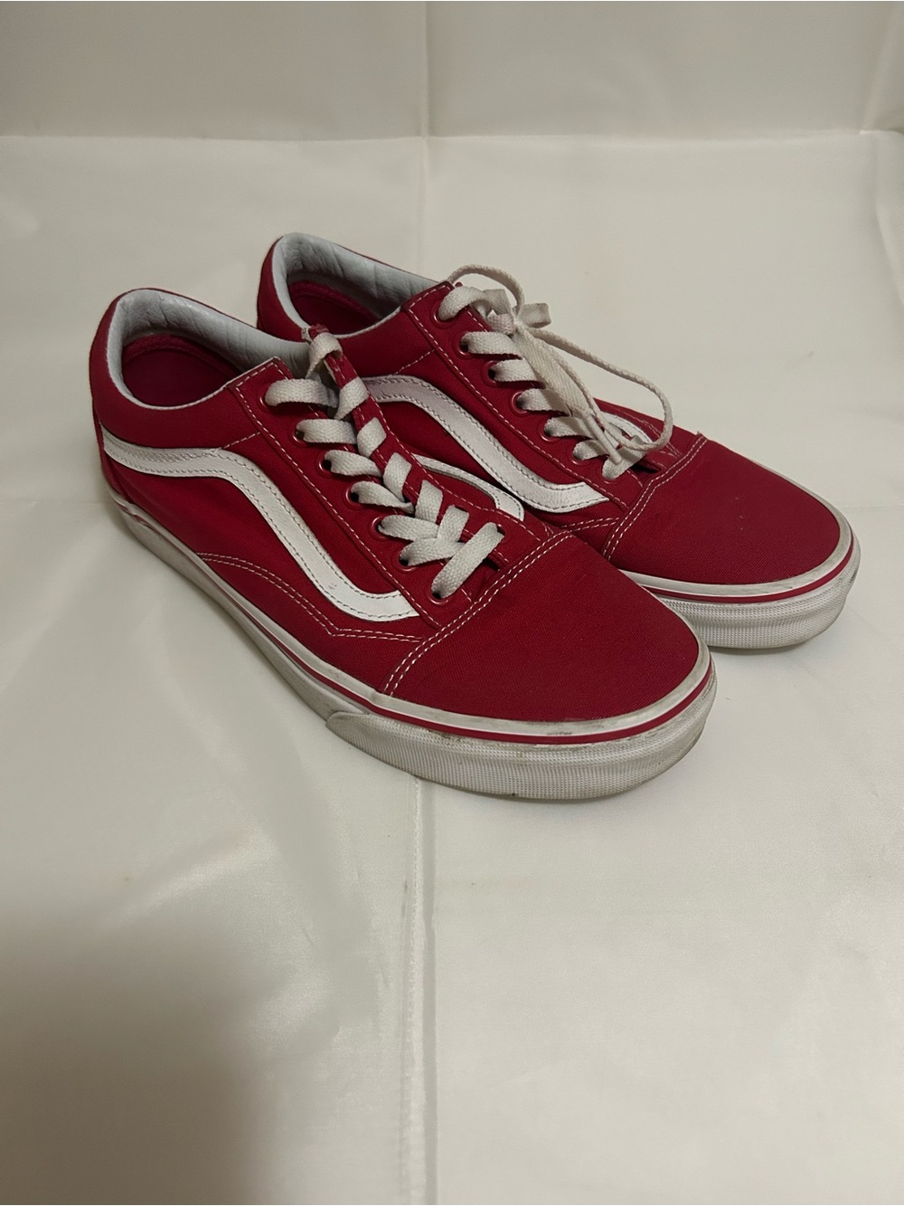 Red Vans Old Skool sneakers with white stripes.